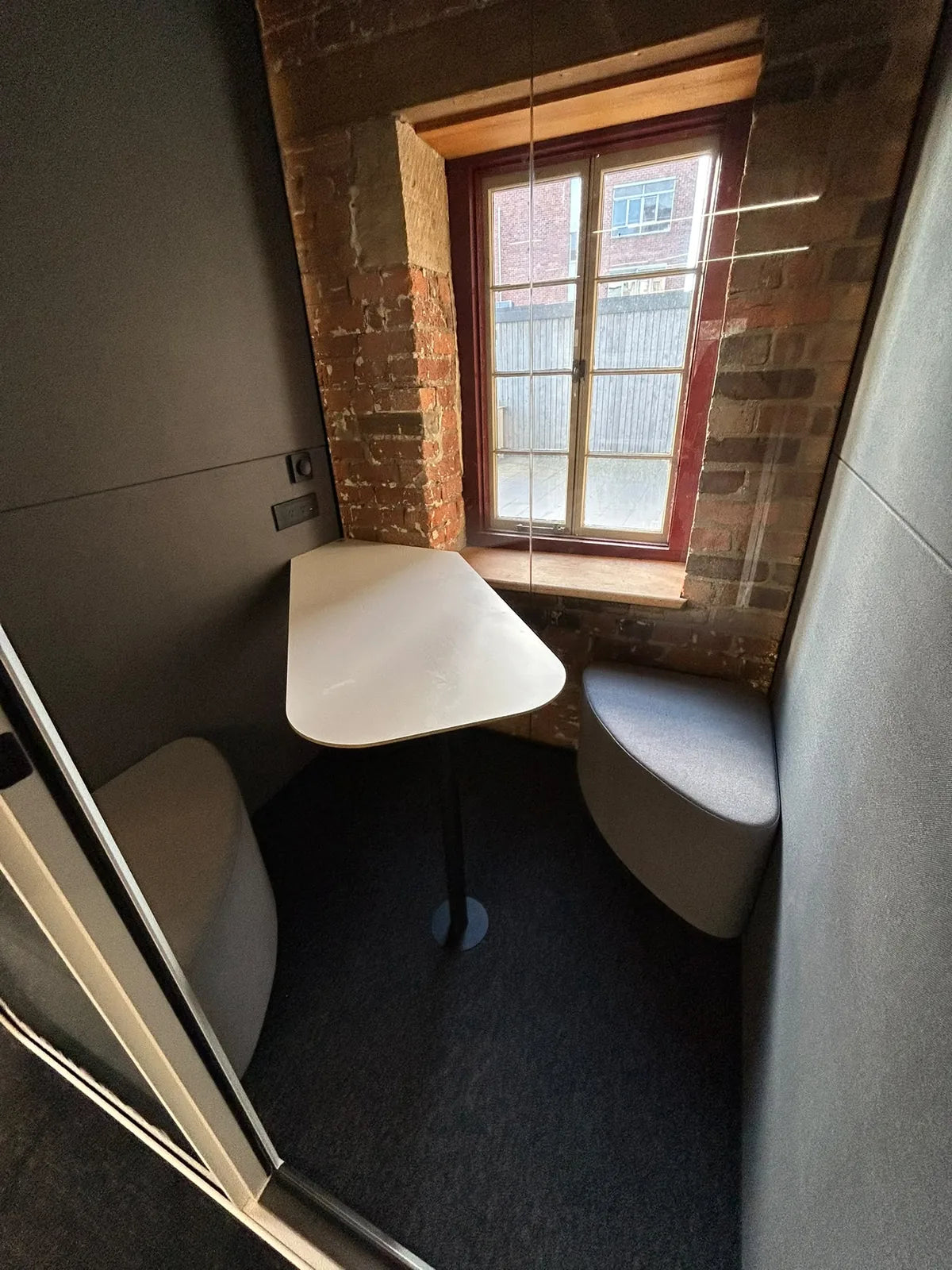 Interior of a FocusPod Duo with a shared table and grey seating in the Launceston installation.