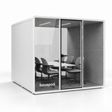 FocusPod Max front-left angled studio view showing its deep enclosure and six-chair meeting layout.