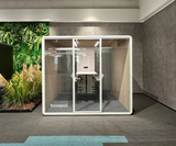 FocusPod Max installed beside a living green wall, with optional bar-and-stool furniture and the white FocusPod logo low on the left glass.